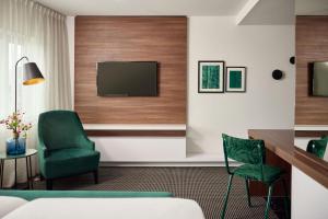 a hotel room with a television and a green chair at Van der Valk Zaltbommel-A2 in Zaltbommel