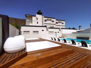 a deck with white furniture and a swimming pool at Hotel Astoria in Villa Carlos Paz