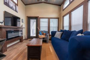 a living room with a blue couch and a tv at Deers Den River- Luxury Tiny Home on River in Bryson City