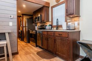a kitchen with wooden cabinets and stainless steel appliances at Deers Den River- Luxury Tiny Home on River in Bryson City +13 photos
