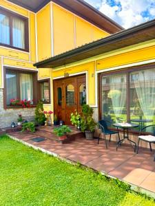 a yellow house with a patio with a table and chairs at Арбория in Koprivshtitsa