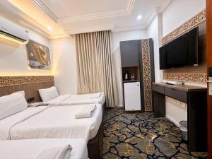 a hotel room with two beds and a flat screen tv at Luluat Al Badaie Hotel in Mecca