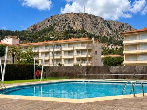 a hotel with a swimming pool in front of a mountain at Festasol - Apartament Estartit in Torroella de Montgrí