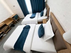 three beds with blue pillows in a room at AERON hotel in Yakkasaray +39 photos