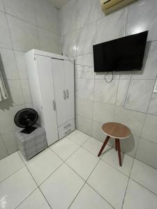 a bathroom with a toilet and a stool and a tv at Jardim Tropical in Bayeux +2 photos