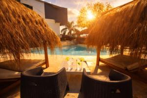 a pool with chairs and umbrellas and a table with drinks at Hotel Storge in Villa Carlos Paz