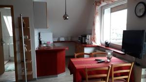 a kitchen with a red table with chairs and a window at Haus Haase in Prenzlau