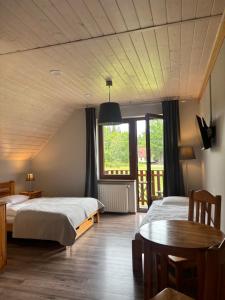 a bedroom with two beds and a table and a window at Doboszowka in Lasowka
