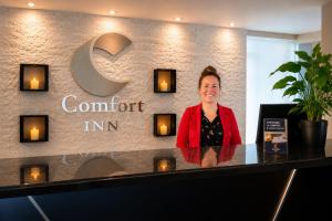 a woman standing at a counter in front of a sign at Comfort Inn in Saint-Georges