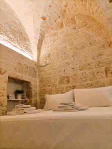 a bed in a room with a stone wall at La Carruba in Ceglie Messapica