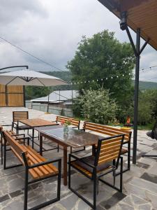 eine Terrasse mit Tischen, Bänken und einem Sonnenschirm in der Unterkunft BruD ԲՐՈՒԴ in Debed
