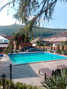 a swimming pool with two benches in front of a house at Hammam Spa Villa DAROSO in Kosiv