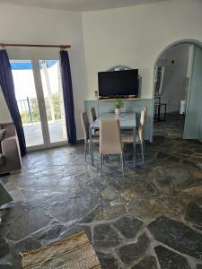 a dining room with a table and chairs and a television at Ioannis Appartements Glossa in Glossa