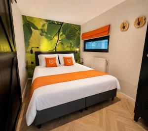 a bedroom with a large bed with orange pillows at TinyLodge with hottub in Diessen