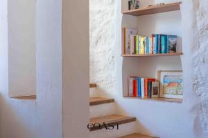 a book shelf with books on it next to a wall at San Pantaleo Charme in San Pantaleo