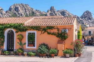 a building with plants in front of a mountain at San Pantaleo Charme in San Pantaleo