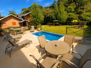 a patio with a table and chairs next to a pool at Pousada Charme da Montanha in Monte Verde