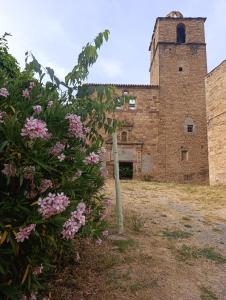 an old brick building with a tower and pink flowers at Albergue de Ruesta in Ruesta