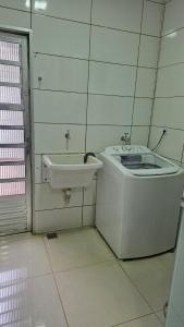 a white bathroom with a sink and a tub at Casa Completa e Confortável para sua Estadia in Ribeirão Preto