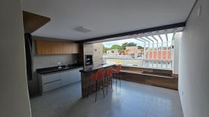 a kitchen with a counter and chairs and a large window at Casa Completa e Confortável para sua Estadia in Ribeirão Preto