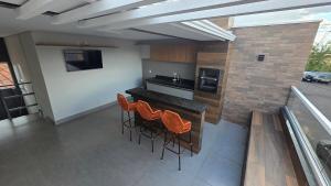 a kitchen with a bar with orange chairs on a balcony at Casa Completa e Confortável para sua Estadia in Ribeirão Preto +15 photos