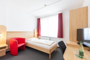 a hotel room with a bed and a red chair at Akademiehotel Jena in Jena