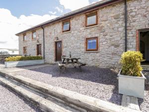 a stone house with a picnic table in front of it at Bwthyn Y Wennol in Llanddulas