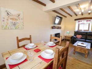 a dining room and living room with a table and chairs at Bwthyn Y Wennol in Llanddulas