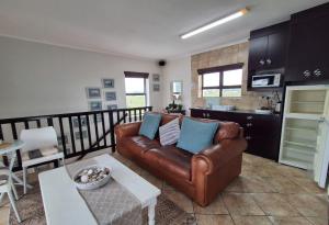 a living room with a leather couch and a table at Beachway on Golden Mile in St. Helena Bay