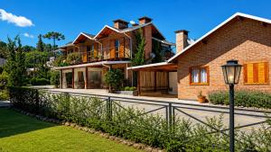 a house with a fence in front of it at Pousada Charme da Montanha in Monte Verde