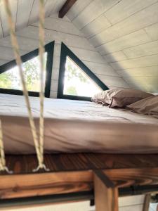 a bed in a hammock in a room with a window at Entre ciel et champs in Capendac
