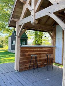 a patio with two bar stools under a wooden pergola at Entre ciel et champs in Capendac