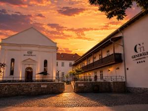 a building with a sunset in the background at Generalis Wine Hotel in Tokaj