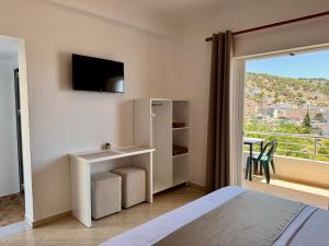 a bedroom with a bed and a tv and a balcony at Apartments Klajdi in Sarandë