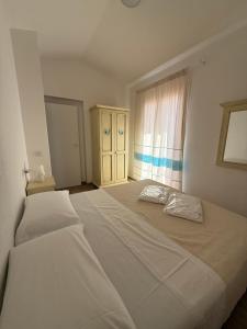 a large white bed in a bedroom with a window at Residence Le Onde in Badesi +75 photos