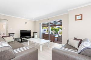 a living room with two couches and a tv at Ravens 9A in Bloubergstrand