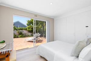 a bedroom with a bed and a sliding glass door at Ravens 9A in Bloubergstrand +22 photos