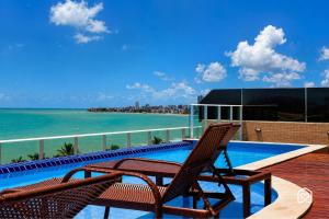 two chairs sitting on a deck next to a swimming pool at Mar Bello in Ilha da Restinga