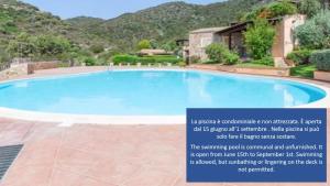 a large swimming pool with a mountain in the background at Torretta con vista mozzafiato in Chia