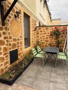 a patio with a table and chairs next to a building at L'Escapade Normande in Caen