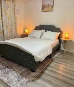 a bed in a bedroom with two tables and two lamps at Cozy 1-Bed Basement Suite in Calgary
