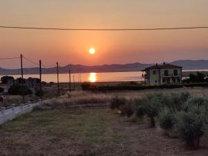 a sunset over the ocean with a house in the foreground at Panorama Apartment 1 in Moúdhros