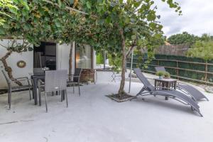 a patio with a table and chairs and a tree at Cabañita rústica con piscinas in Cambre