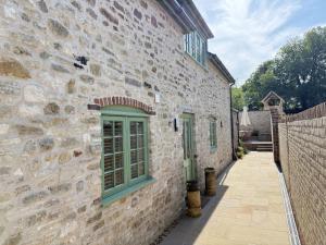a stone building with green windows and a fence at Sunray Cottage in Weymouth