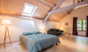 a bedroom with a bed and a couch in a room at L'Oustal del Sully - Villa d'exception avec piscine, proche lac de Pareloup in Prades-Salars