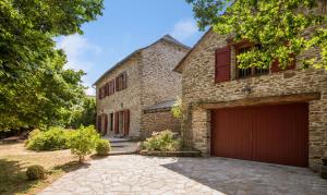 a brick house with a red garage at L'Oustal del Sully - Villa d'exception avec piscine, proche lac de Pareloup in Prades-Salars