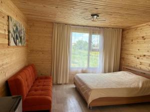 a bedroom with a bed and a couch and a window at Экохаус Hemingway 1 in Borovoye