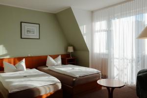 a hotel room with two beds and a window at Schlossberghotel Greiz in Greiz