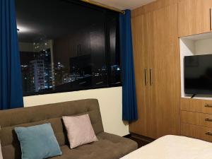 a bedroom with a couch and a window with a city at Amplia suite cerca a La Carolina - Av 6 Diciembre in Quito