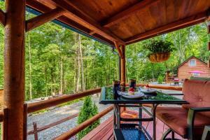 a table on a porch with a view of the woods at Starry Nights in the Smokey Mountains with Hot Tub Pet Friendly Cabin A in Elizabethton